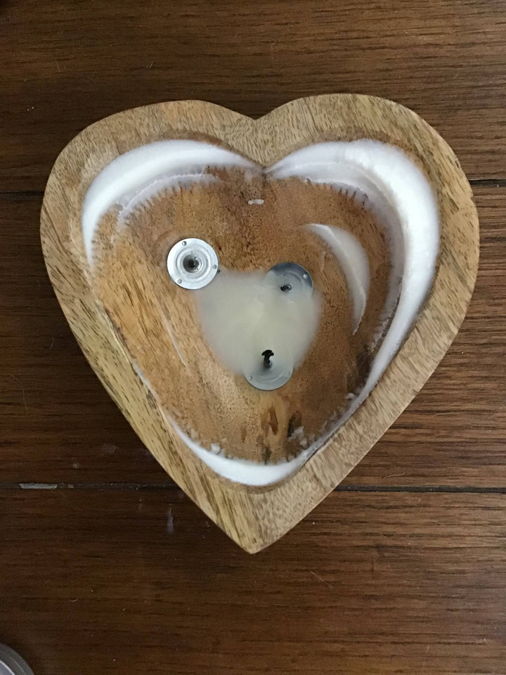 Heart-shaped wooden candle with a white circular design on a wooden surface
