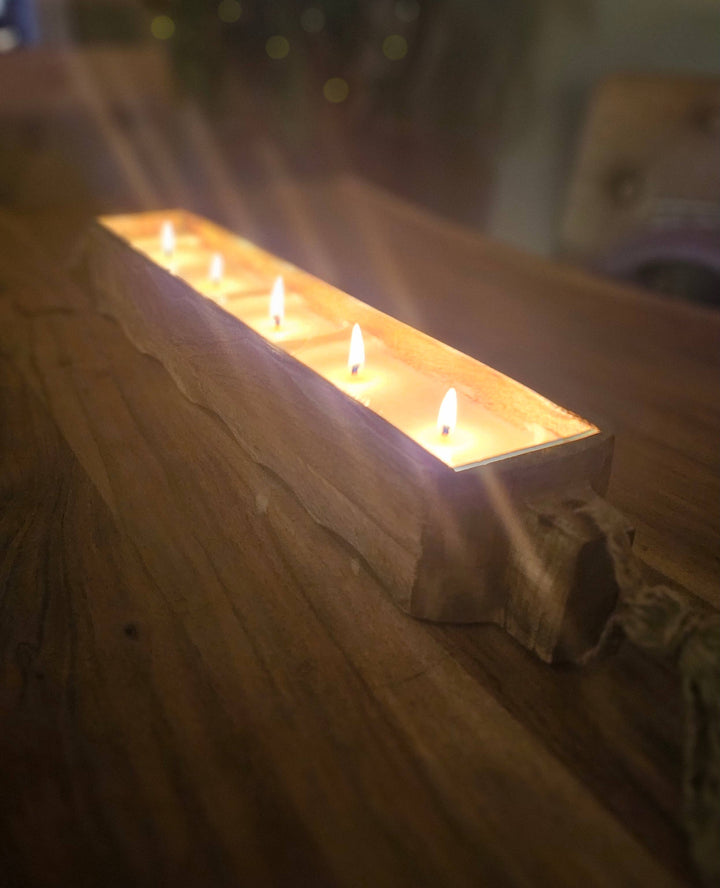 Wooden candle holder with lit candles on a wooden surface