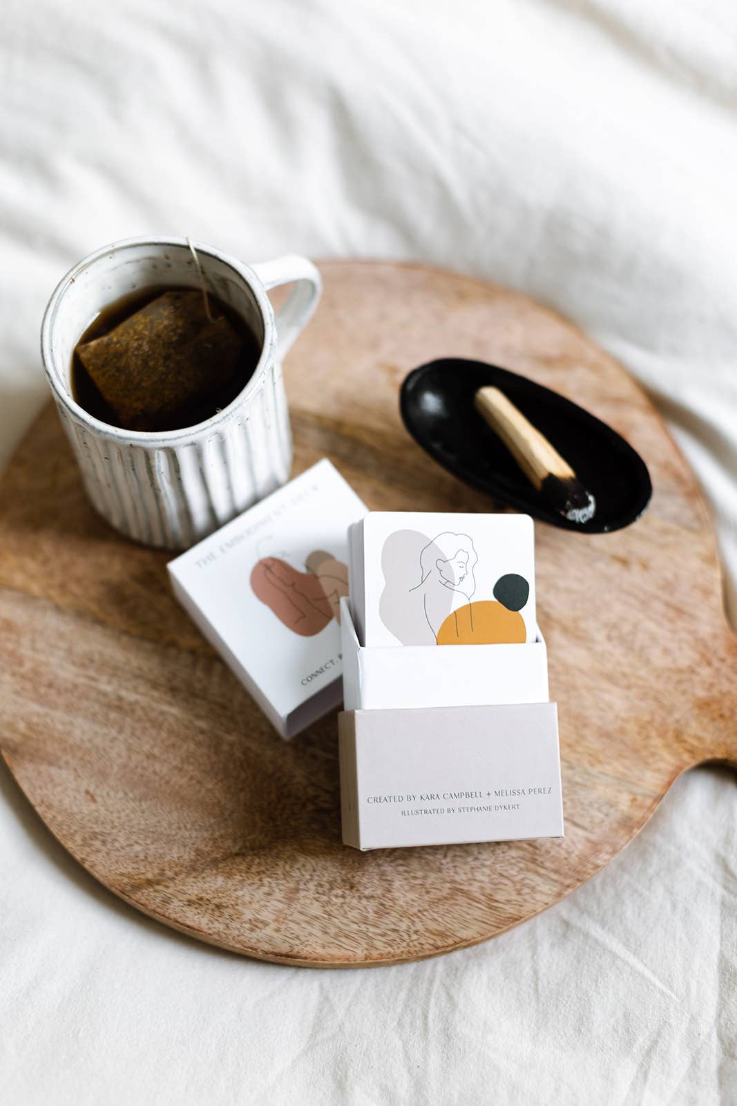 Tea bag in a cup with two tea box packages on a wooden tray.