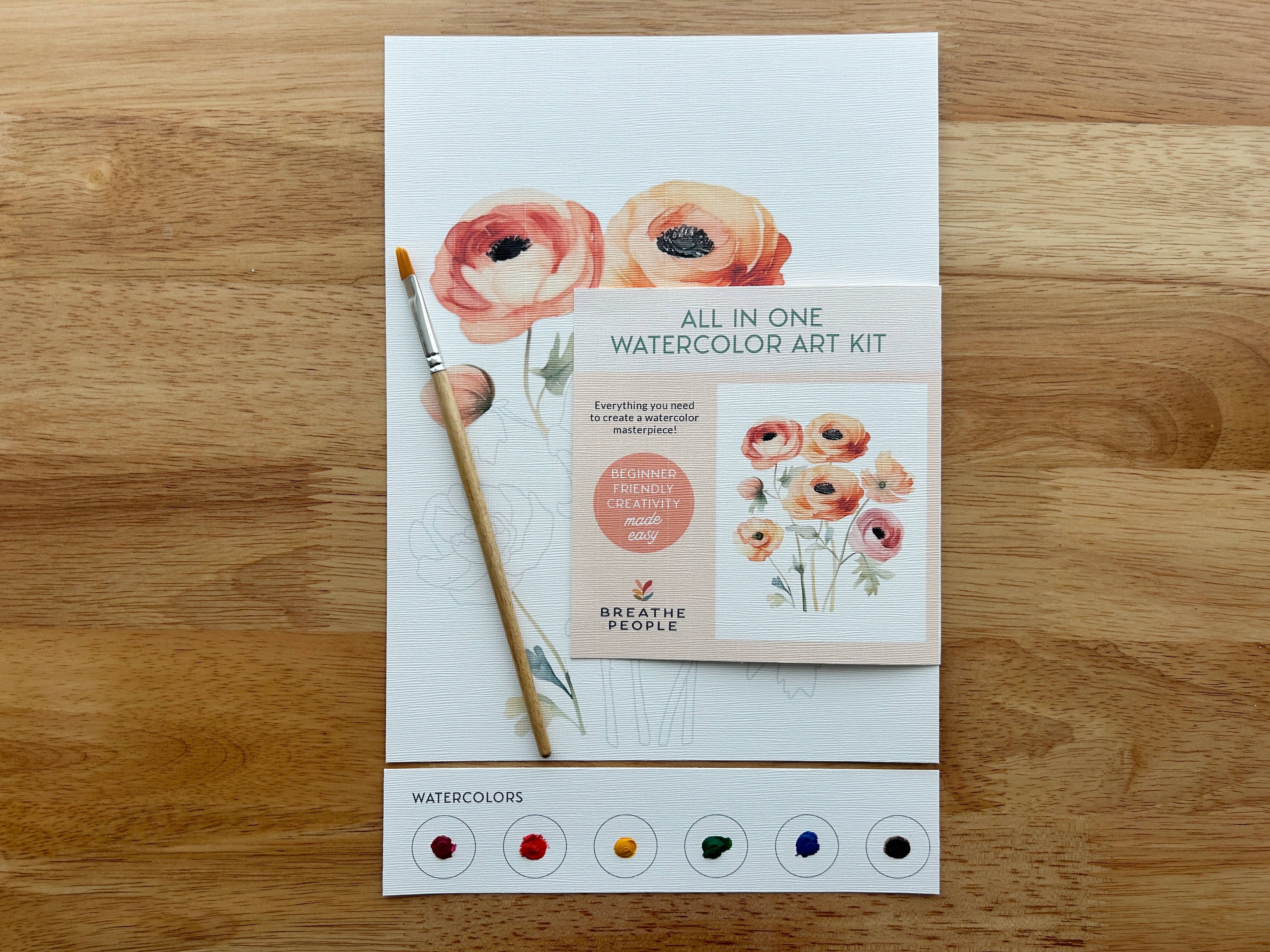 All-in-one watercolor art kit with a brush on a wooden surface