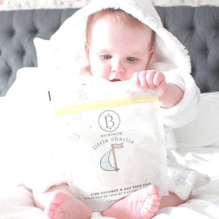 Baby holding a product labeled 'Bathorium little charlie'
