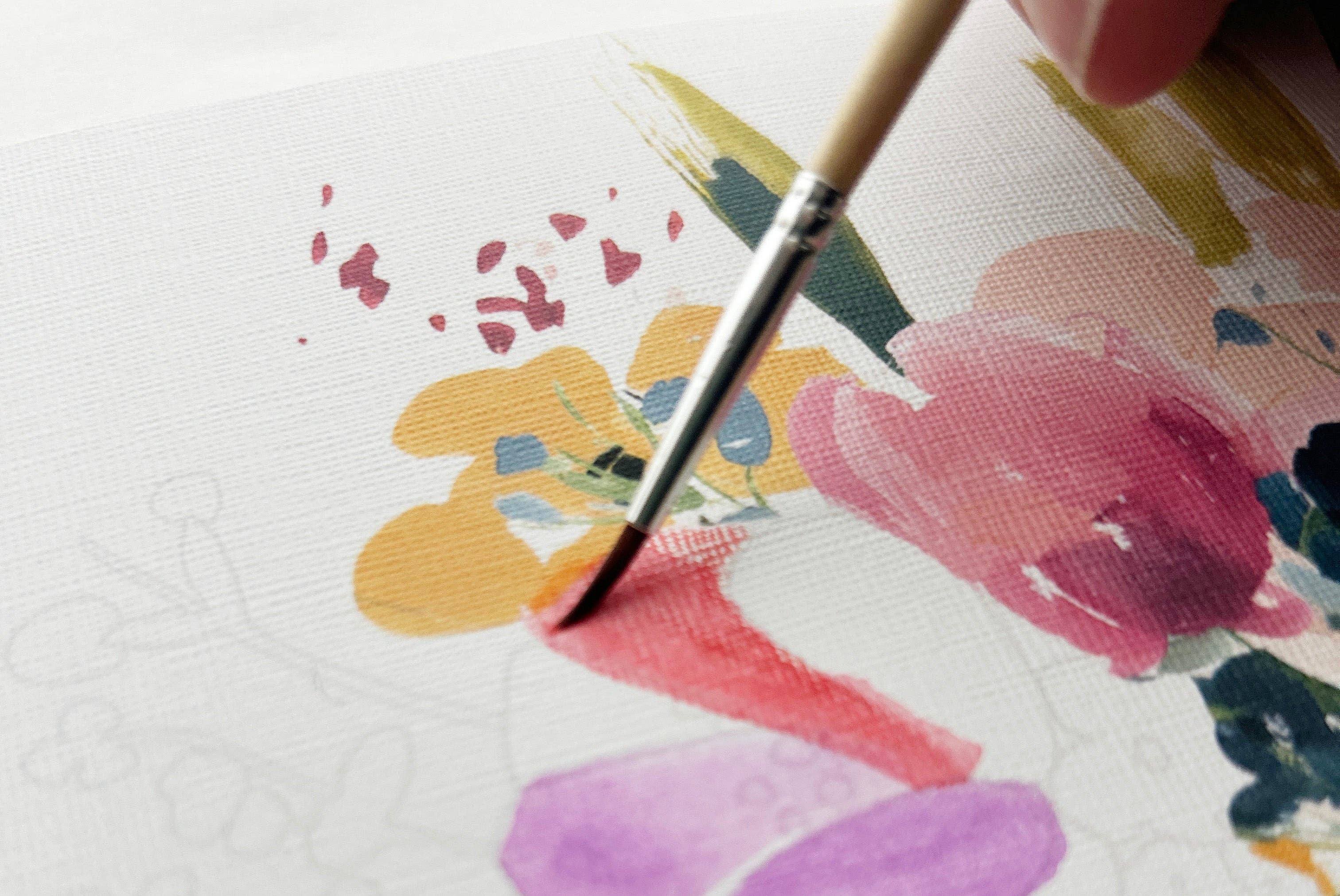 Paintbrush applying paint to a floral design on paper