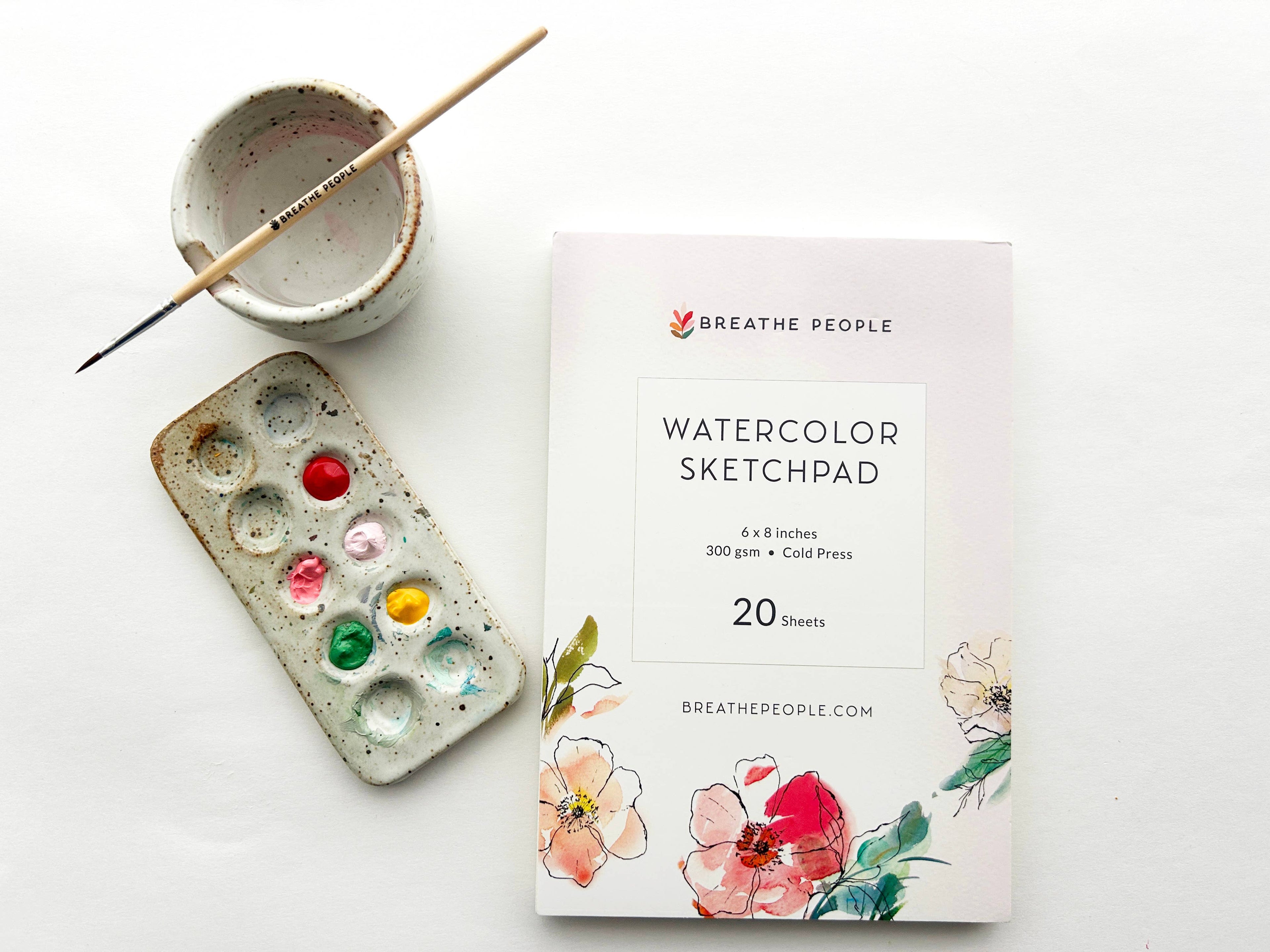 Watercolor sketchpad with paint palette and brush