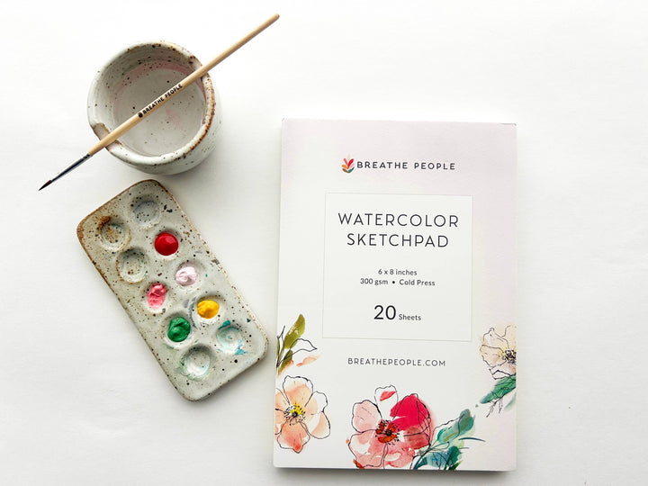 Watercolor sketchpad with paint palette and brush