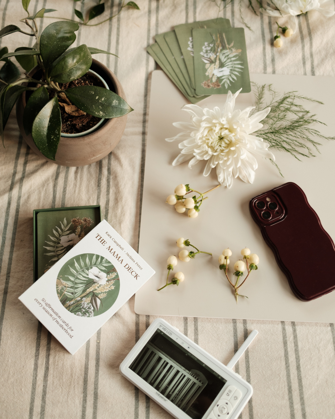 Tabletop with cards, phone, plant, and flowers on a checkered tablecloth