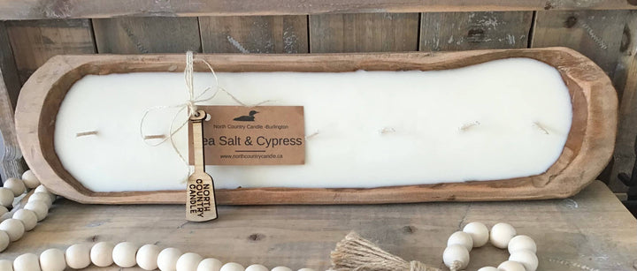 White candle in a wooden holder with a label on a wooden surface